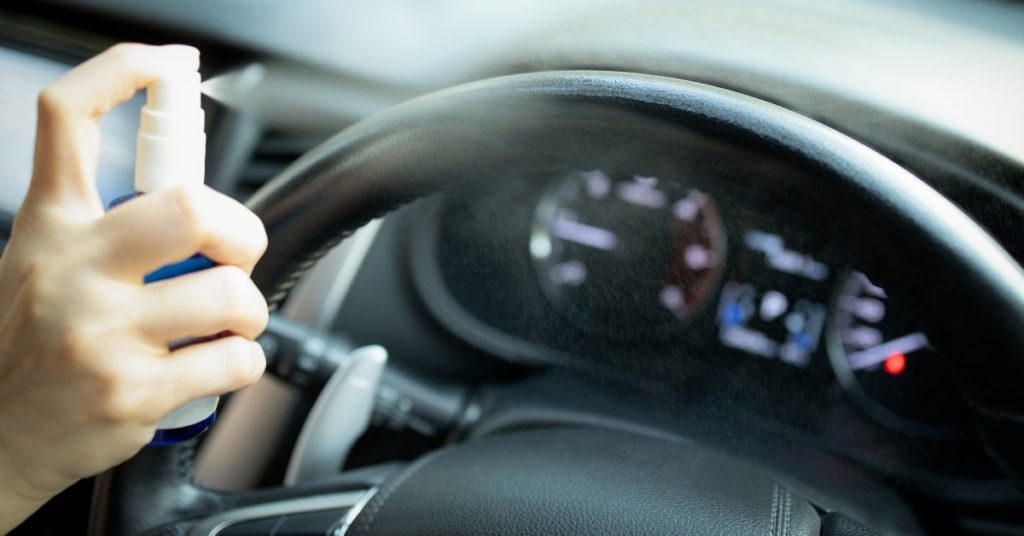 Woman spraying a clear liquid on the steering wheel