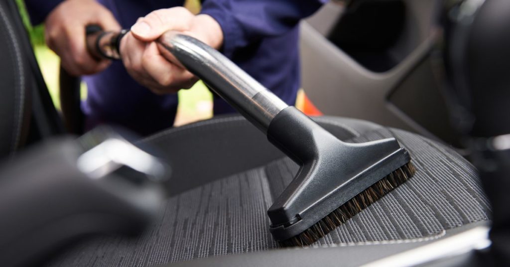 Man vacuuming the car seat