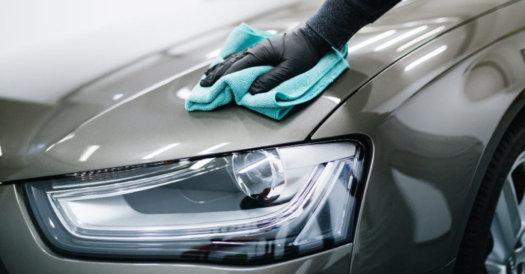 Person polishing a silver sedan car