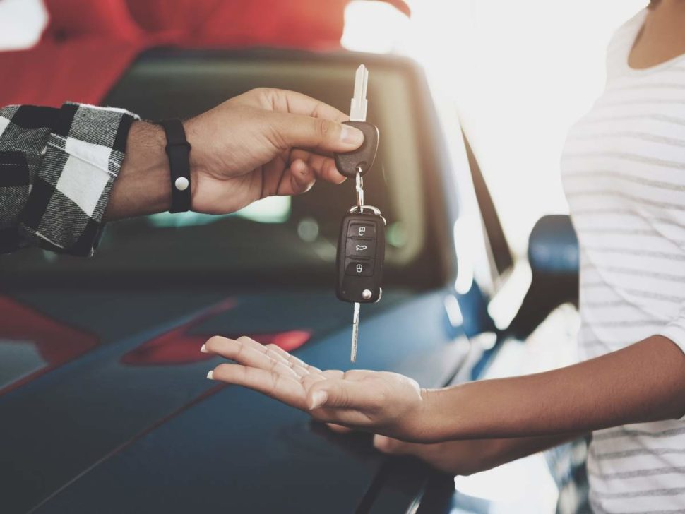 People handing over their car keys to a new buyer