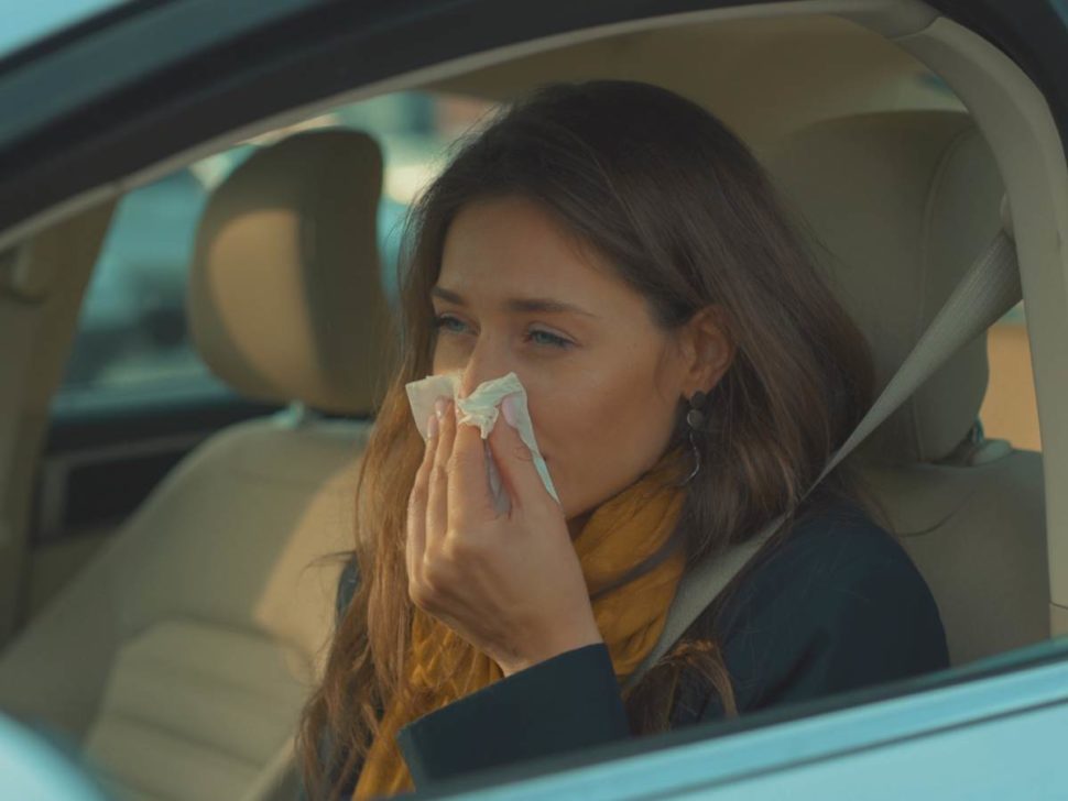 Woman sneezing in her car