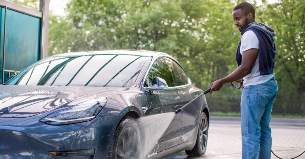 handsome man washing his electric car