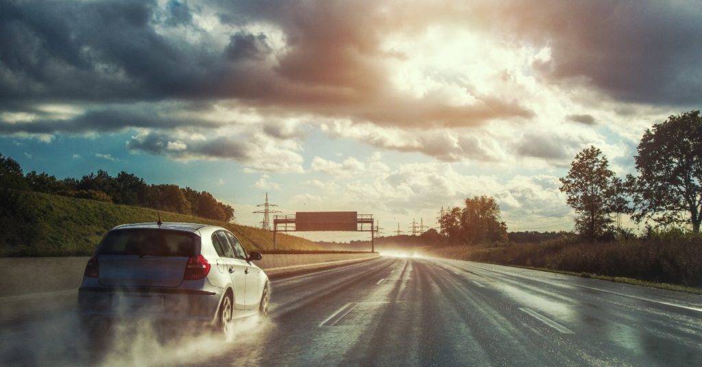 Hatch Back driving along wet road 