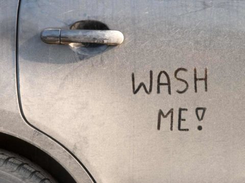 Dirty car with wash me written on it