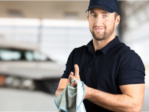 Handsome mechanic wipes grease off his hands with a rag